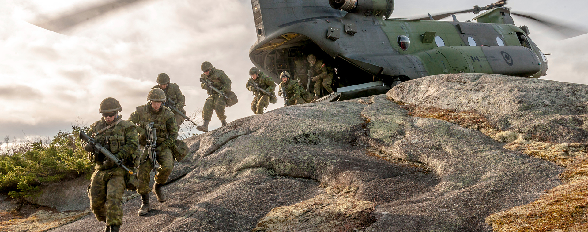 Des militaires canadiens, en ligne, débarquent de leur hélicoptère d’attaque. Munis de leurs armes et équipements de combat, ils sont déterminés, concentrés et prêts à affronter toutes les aventures qui les attendent sur un territoire étranger.